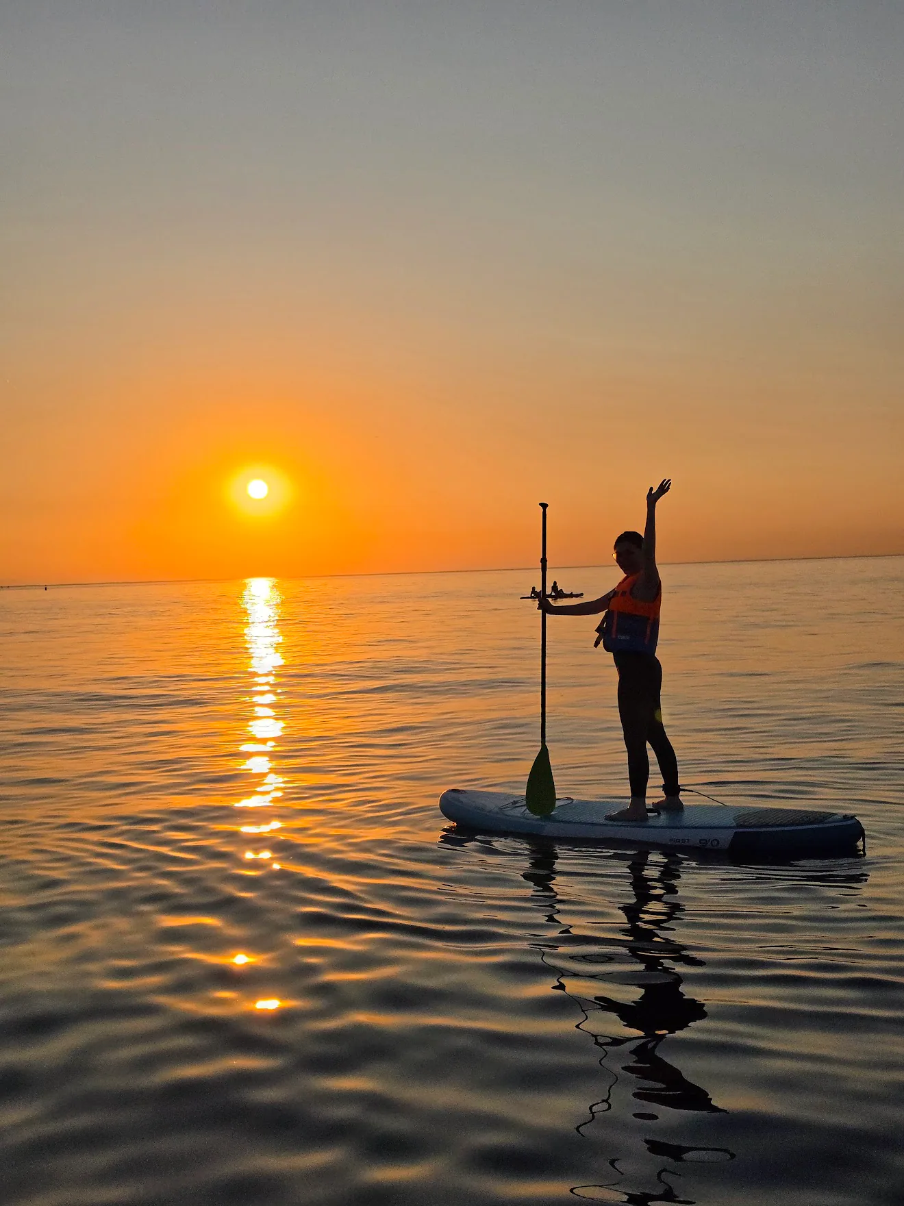 A silhouetted paddler on the water at sunset in Barcelona, Spain.