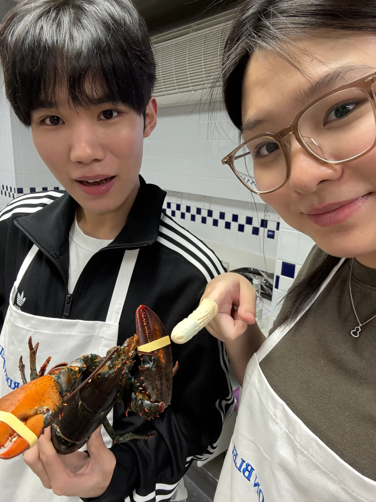 Christina and another attendee holding a lobster during a cooking class at Le Cordon Bleu in London.
